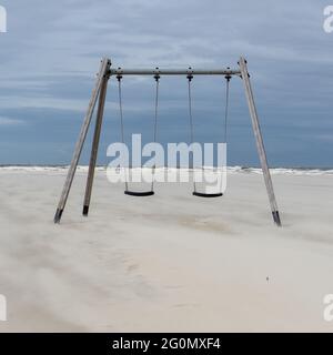 Deux balançoires sur une plage de sable doré vide avec la mer des Wadden du nord de l'Allemagne en arrière-plan Banque D'Images