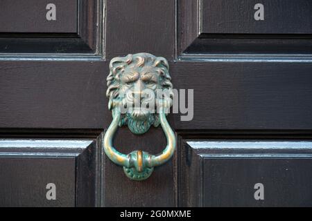 Des lions anciens et abîmés sont à la tête d'une porte en bois sombre. Banque D'Images