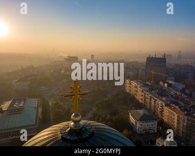 Photo aérienne de la croix d'or au sommet de la coupole du temple de Saint Sava à Belgrade avec pollution de l'air en arrière-plan Banque D'Images