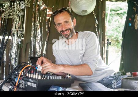 Un homme travaillant sur scène dans un festival de musique en tant qu'ingénieur du son aidant avec la musique. Banque D'Images