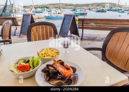 Plat de mer avec frites et salade dans un restaurant dans le port de la ville de Marsaxlokk, Malte Banque D'Images