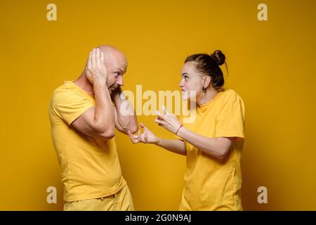 Abus. Une femme furieuse crie et grimpa l'homme qui, dans la peur, couvrait ses oreilles avec ses mains. Concept de violence domestique. Banque D'Images