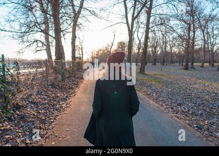 Une jeune fille en manteau d'hiver se promenant dans un parc naturel Banque D'Images