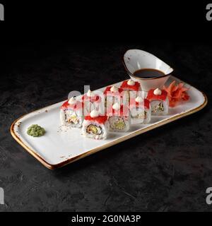 Petits pains à sushi Kawasaki Maki avec riz, anguille, crabe des neiges, avocat, sauce chaude, Tobiko caviar sur fond noir. Menu sushi. Cuisine japonaise. Banque D'Images