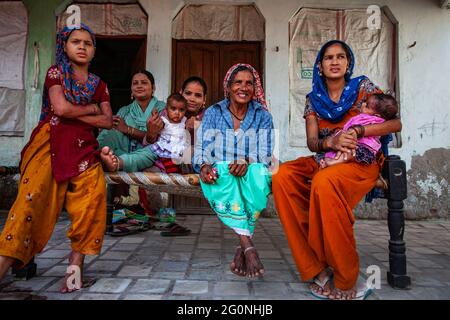 Une famille indienne heureuse avec des enfants et une femme devant une maison avec une robe traditionnelle Banque D'Images