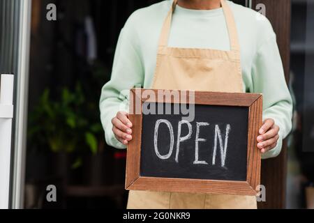 Vue rognée du barista afro-américain tenant un tableau noir avec des lettres ouvertes près du café Banque D'Images