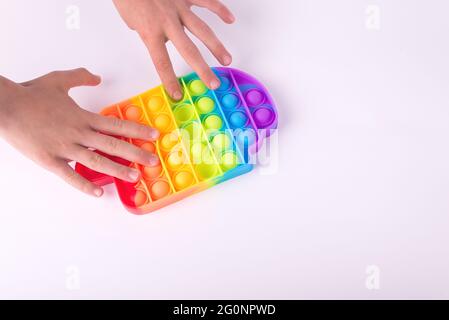 Les enfants jouent à la main avec le jouet de violon coloré arc-en-ciel pop il isolé sur le blanc. Banque D'Images