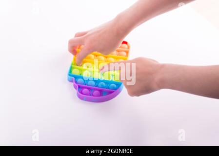 Les enfants jouent à la main avec le jouet de violon coloré arc-en-ciel pop il isolé sur le blanc. Banque D'Images