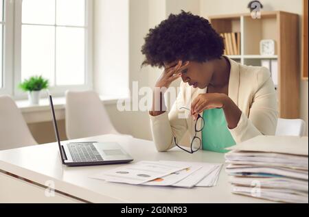 Femme d'affaires afro-américaine fatiguée des routines de travail et des délais souffre de maux de tête. Banque D'Images