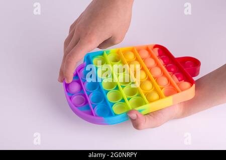 Les enfants jouent à la main avec le jouet de violon coloré arc-en-ciel pop il isolé sur le blanc. Banque D'Images