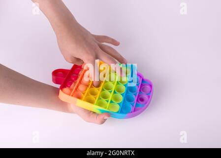 Les enfants jouent à la main avec le jouet de violon coloré arc-en-ciel pop il isolé sur le blanc. Banque D'Images