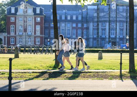 Münster, Allemagne. 2 juin 2021. Un groupe de jeunes marchent devant Münster Schloss (palais de la ville) par une chaude journée ensoleillée avec des températures autour de 28 degrés dans la ville universitaire de Münster. Le nombre de Covid a chuté régulièrement en Allemagne, ce qui a conduit à un assouplissement supplémentaire des restrictions. Münster se classe régulièrement parmi les villes les plus à incidence la plus faible de NRW. Credit: Imagetraceur/Alamy Live News Banque D'Images