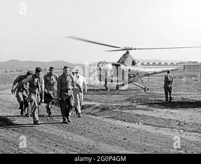 Évacuation des blessés de guerre de Corée. Navy Corpmen Herald B. Williams, James E. Carr et William N. Shipworth aident à transporter un blessé d'un hélicoptère d'évacuation HO3S-1 du corps des Marines des États-Unis vers un hôpital en Corée. L'hélicoptère provient de l'escadron VMO-6. Banque D'Images