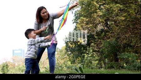 La mère et le fils asiatiques lancent un cerf-volant dans le parc du jardin Banque D'Images