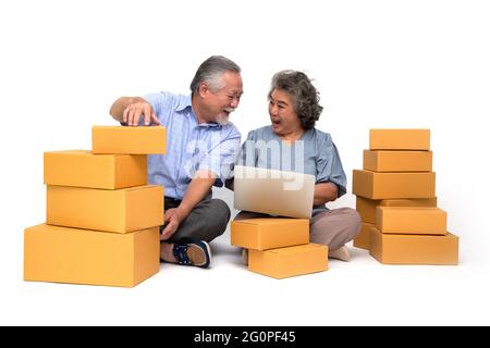 Senior asiatique couple démarrage petite entreprise freelance tenant boîte de colis et ordinateur portable et assis sur le sol isolé sur fond blanc, en ligne Banque D'Images