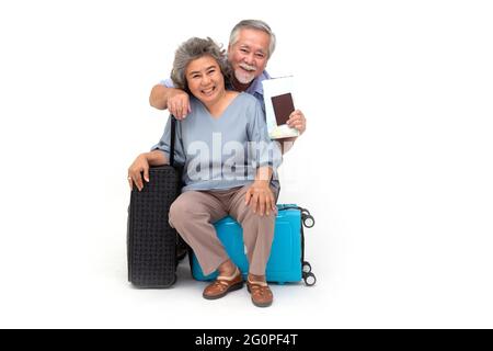 Couple asiatique senior assis sur un sac de voyage isolé sur fond blanc, les voyageurs et le concept de tourisme Banque D'Images