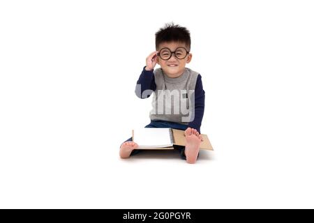 Portrait d'un adorable petit garçon asiatique portant des lunettes et lecture d'un livre isolé sur fond blanc Banque D'Images