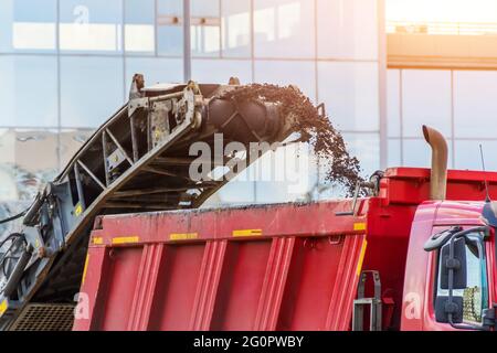 La fraiseuse de chaussée enlève l'asphalte usagé et le charge dans un camion-benne. Réparation de la chaussée asphaltée de la route Banque D'Images