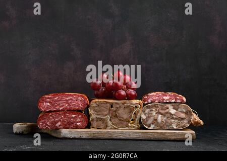Planche à découper en bois avec rouleau de viande de porc bouilli, rouleau de langue de bœuf et saucisse maison Banque D'Images