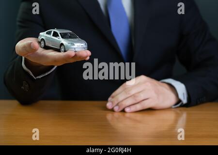 Homme d'affaires en banque tenant le modèle de voiture, nouvelle location de voiture achat prêt concept Banque D'Images