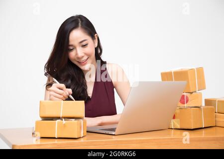 Les femmes asiatiques colis emballage sur la table et fond blanc, femme recevoir boîte en carton à partir de l'achat en ligne de commande, Expédition et livraison achats et b Banque D'Images