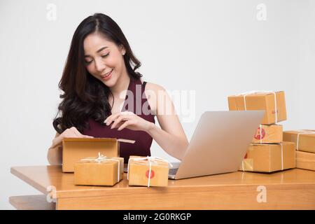 Les femmes asiatiques colis emballage sur la table et fond blanc, femme recevoir boîte en carton à partir de l'achat en ligne de commande, Expédition et livraison achats et b Banque D'Images