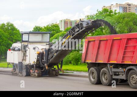 La fraiseuse de chaussée enlève l'asphalte usagé et le charge dans un camion-benne. Réparation de la chaussée asphaltée de la route Banque D'Images