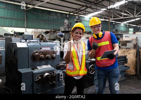 Portrait de la femme et de l'homme travailleur manuel est debout avec confiance et porte un casque de sécurité dans l'usine de l'industrie lourde Banque D'Images