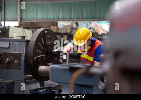 Ingénieur mécanique asiatique exploitant une machine de tournage industrielle et travaillant dans une usine industrielle Banque D'Images