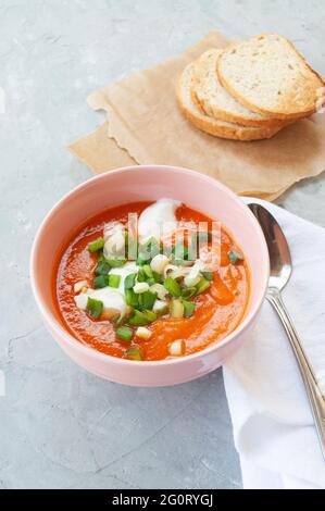 Soupe froide de gaspacho fraîchement cuite. Soupe traditionnelle espagnole de tomates froides de légumes frais crus avec tranches de pain grillé sur une table de couleur grise. Banque D'Images