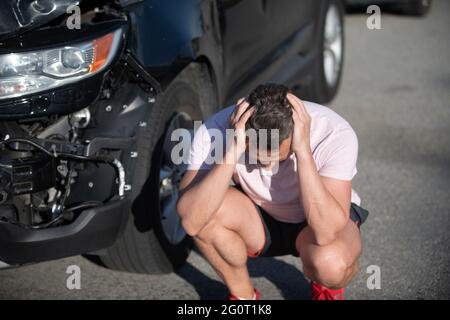 accident de voiture. conducteur frustré après un accident de la route. homme avec auto cassé sur la route. Banque D'Images