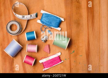 Rouleaux de fil à coudre et accessoires sur table en bois avec espace de copie. Banque D'Images