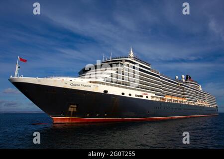 Le bateau de croisière Queen Victoria se trouve sur une mer calme tout en étant ancré au large de Torbay à Devon, au Royaume-Uni. Banque D'Images