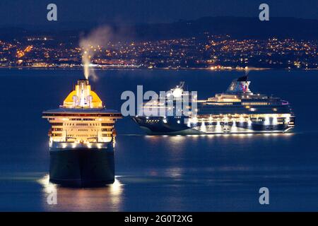 Les bateaux de croisière Queen Mary 2 et Marella Explorer 2 sont ancrés dans des eaux calmes au crépuscule au large de la côte de Torbay, Devon, Royaume-Uni. Banque D'Images