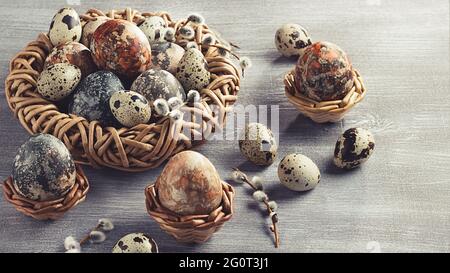 Composition de Pâques - plusieurs oeufs en marbre peints avec des teintures naturelles dans un nid en osier et des paniers. Banque D'Images