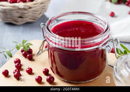 Pot en verre avec sauce maison aux baies de lingonis. Mise en conserve de la sauce aux baies de lingonis. Banque D'Images