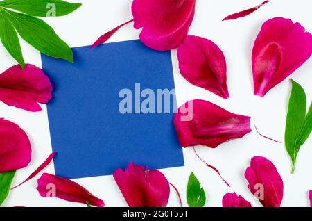 Une feuille propre de papier bleu maquette une carte de vœux. Feuille de papier sur pétales roses, concept pour le jour de la Saint-Valentin, le jour de la mère, l'anniversaire. Vue Banque D'Images