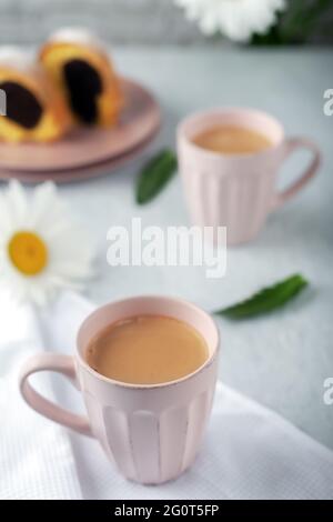 Deux tasses de café fraîchement préparé à la crème avec cupcake et fleurs de camomille Banque D'Images