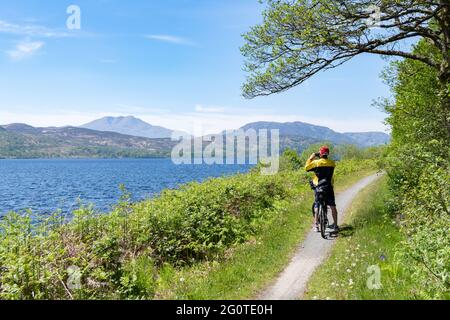 Cycliste sur le chemin des Grands Trossachs le long du côté du Loch Katrine prenant une photo de Ben Lomond, Loch Katrine, Écosse, Royaume-Uni Banque D'Images