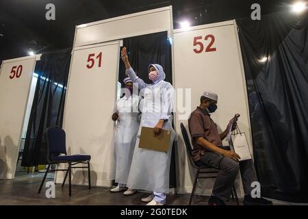 Kuala Lumpur, Malaisie. 29 mai 2021. Un professionnel de la santé fait des gestes au prochain récipiendaire du vaccin au Malaysia International Trade & Exhibition Centre. Le gouvernement malaisien va mettre en place plusieurs nouveaux méga centres de vaccination pour renforcer la capacité de vaccination de Covid-19 et atténuer le problème de surpeuplement. Crédit : SOPA Images Limited/Alamy Live News Banque D'Images