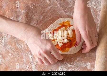 Faire de la pâte par les mains des femmes dorer le fond de la table, vue du dessus. Banque D'Images