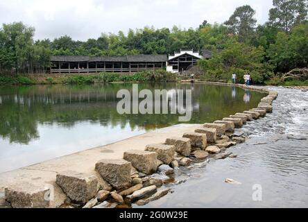 Qinghua dans le comté de Wuyuan, province de Jiangxi, Chine. Des pierres sur la rivière le'an avec roue à eau derrière. Banque D'Images