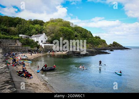 Les gens apprécient leur temps sur la plage dans la pittoresque MCG-yr-Eglwys, Pembrokeshire, au sud du pays de Galles. Il a été signalé que le petit village de bord de mer a plus de maisons de vacances que les résidents permanents avec des locaux étant hors prix du marché de la propriété. Seulement deux des cinquante propriétés du village abritent maintenant des locaux. Banque D'Images