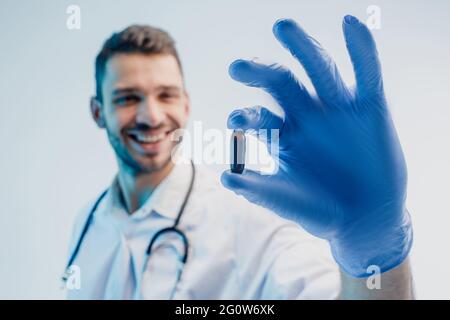 Un médecin européen souriant montrant une pilule médicale Banque D'Images