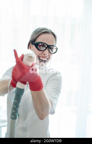 Une femme esthéticienne fait une procédure de rajeunissement laser à diode. Banque D'Images