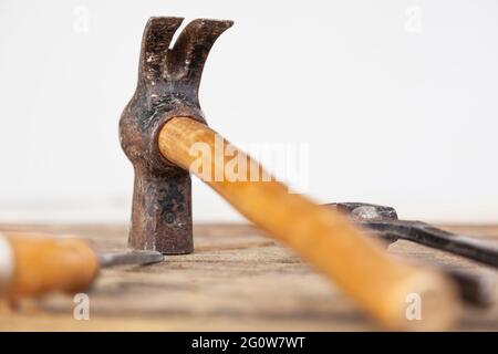 Un marteau de menuisier sur une table. La tête du marteau est au point, le reste est hors point. Il existe également d'autres outils tels que des pinces et un burin Banque D'Images