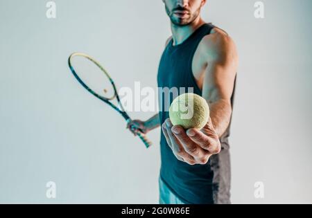 Un sportif tient et montre le ballon de tennis en main Banque D'Images