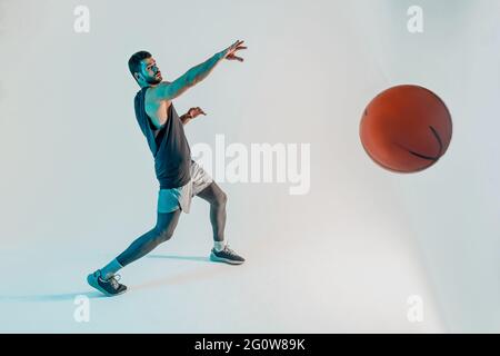Un sportif ciblé lance un ballon de basket-ball en studio Banque D'Images