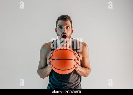 Un sportif surpris tient le ballon de basket-ball en studio Banque D'Images