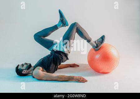 Sportsman faire de l'exercice sur le ballon de fitness en studio Banque D'Images